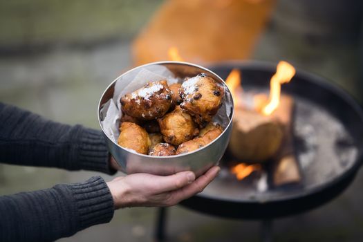 Oliebollen in een airfryer mandje, net opgewarmd en bestrooid met poedersuiker